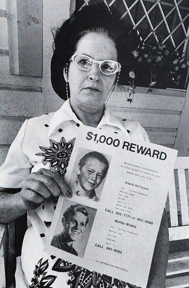 La mère de David Hilligiest brandit un panneau indiquant une récompense de 1 000 dollars pour toute information sur David et son ami Gregory.