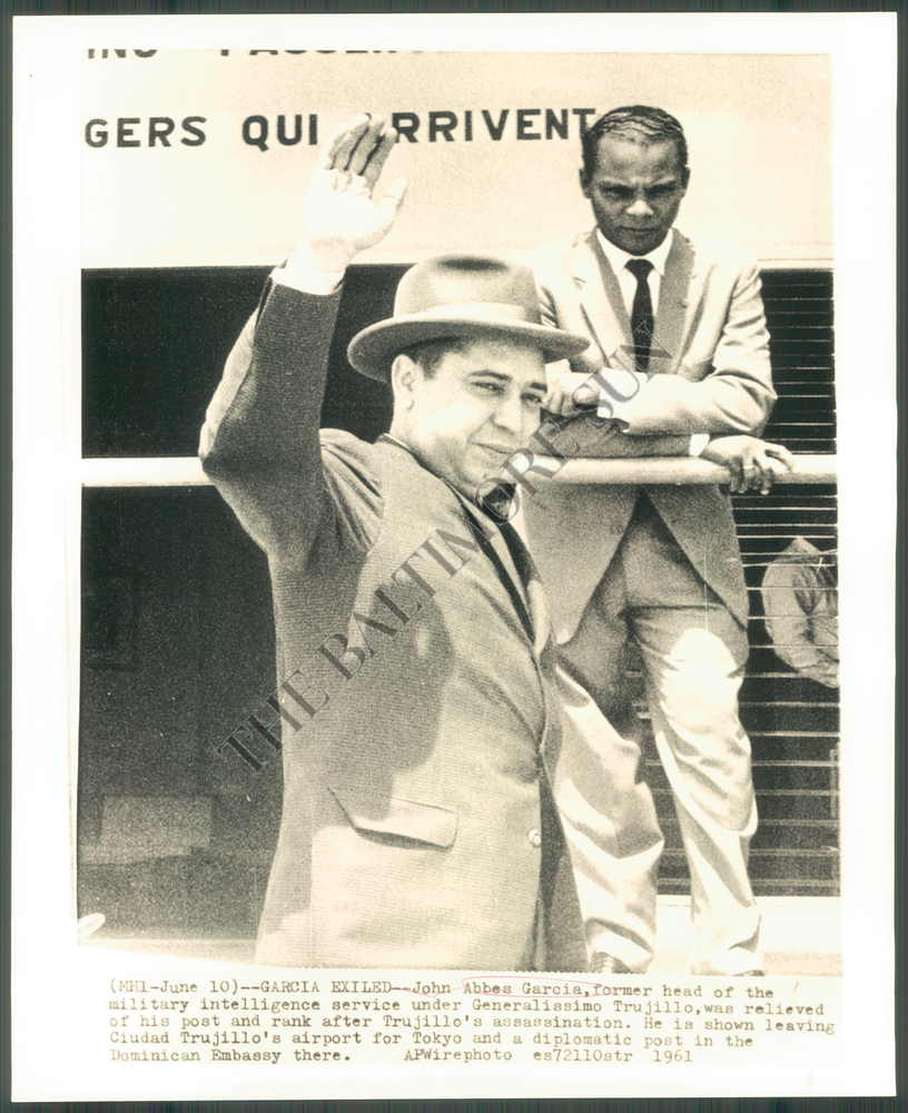 Johnny Abbes García salue alors qu'il quitte la République dominicaine. La photo ne le montre pas, mais il porte un sac noir dans sa main gauche. Crédit : The Baltimore Sun.
