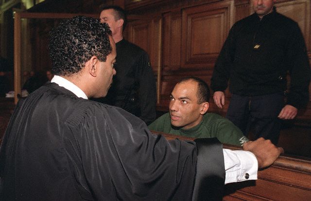 19 mars 2011. Le défendeur Guy Georges parle avec son avocat Alex Ursulet. Source de l'image : Corbis.