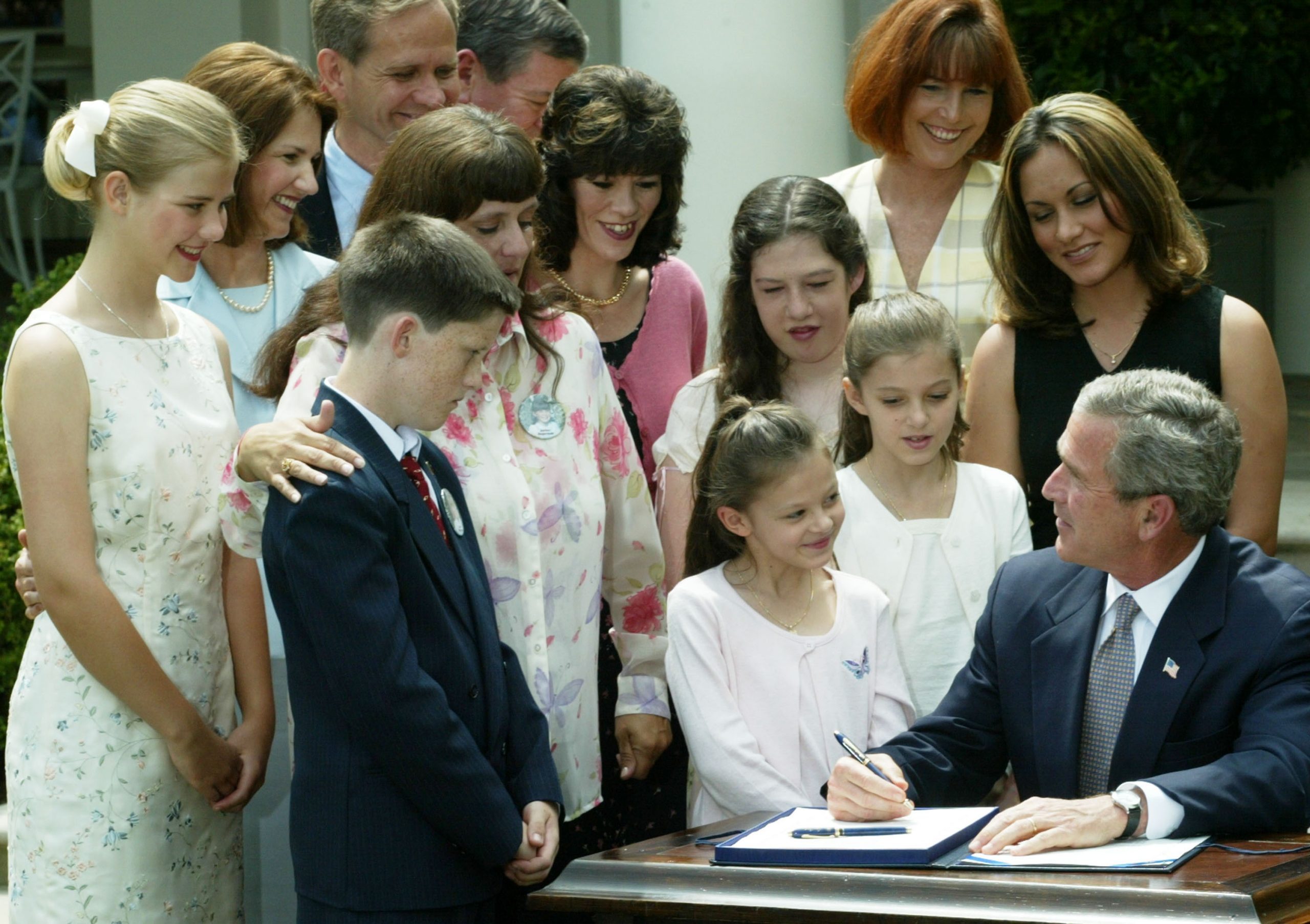 Entouré de familles de victimes d'enlèvement, dont Elizabeth Smart (à gauche), ses parents Lois et Ed, et Donna Norris, la mère d'Amber Hagerman, le président américain George W. Bush (à droite) signe la loi sur l'alerte Amber au Rose Garden de la Maison Blanche le 30 avril 2003.
