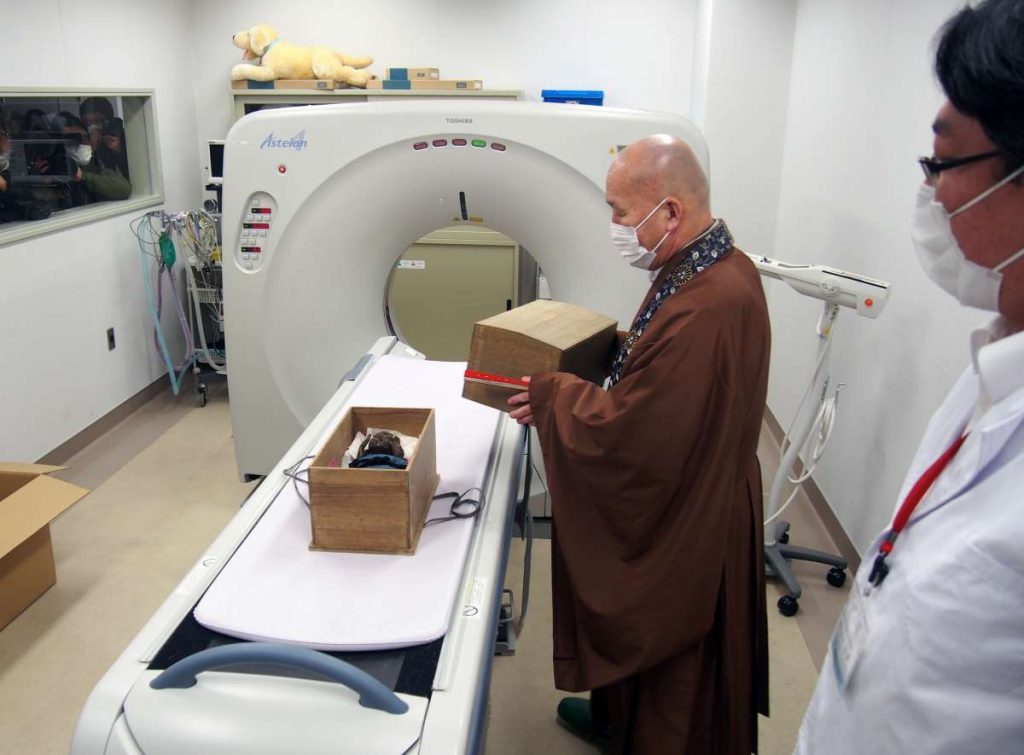 Image : Japan Forward / Le prêtre en chef Kozen Kuida, au centre, place la "momie de sirène" dans un système de tomographie assistée par ordinateur (CT).